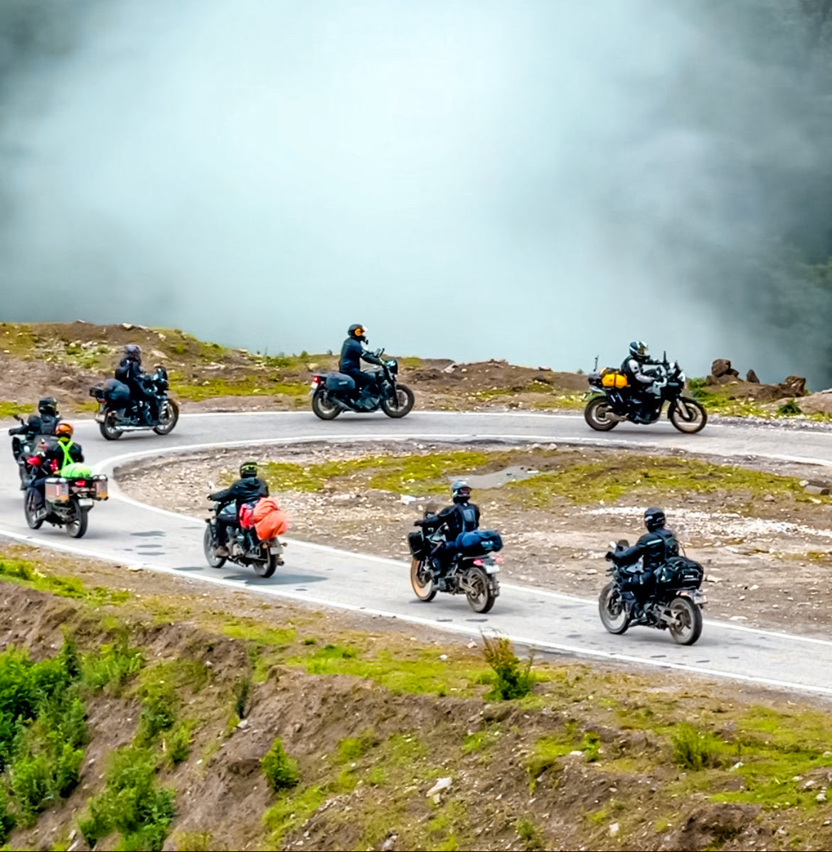 Group of motorcyclists riding on a winding road with a scenic background