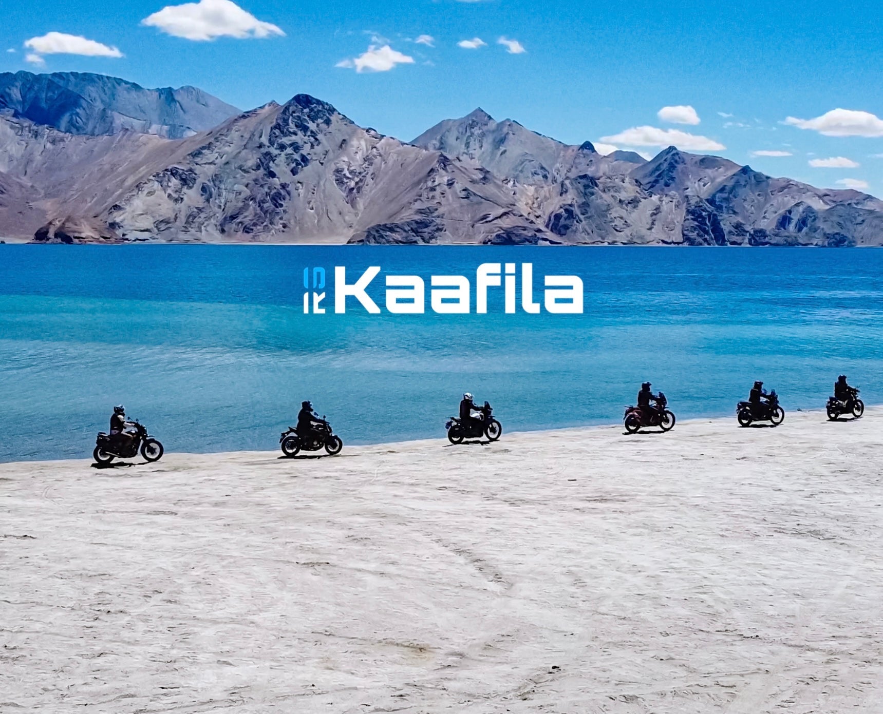 Motorcyclists on a desert landscape with mountains and a lake in the background, featuring the brand 'Kaafila'.